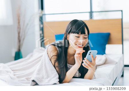 ベッドでスマホを見る若い女性 ベッドでスマホを見る若い女性 133908209