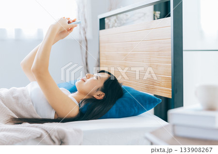 ベッドでスマホを見る若い女性 133908267