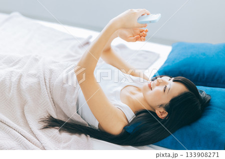 ベッドでスマホを見る若い女性 ベッドでスマホを見る若い女性 133908271