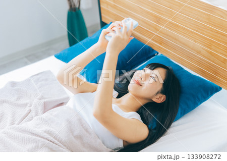 ベッドでスマホを見る若い女性 ベッドでスマホを見る若い女性 133908272