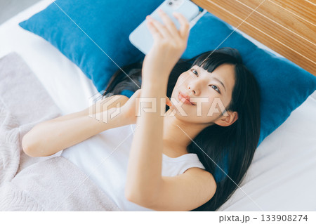 ベッドでスマホを見る若い女性 ベッドでスマホを見る若い女性 133908274