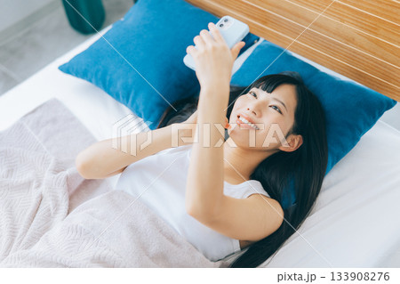 ベッドでスマホを見る若い女性 ベッドでスマホを見る若い女性 133908276
