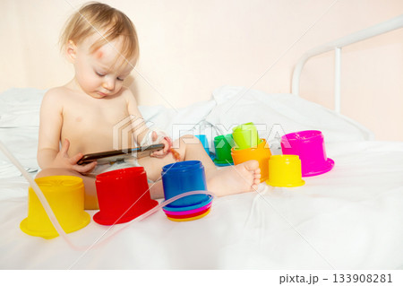child in hospital lying in bed with mobile phone smiling child in hospital lying in bed with mobile phone smiling 133908281