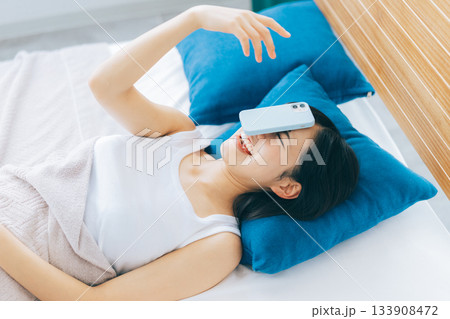 寝落ちしてスマホを顔に落とす女性 133908472
