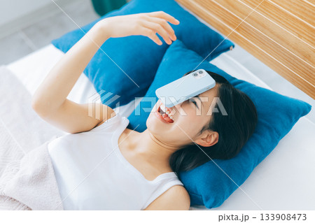 寝落ちしてスマホを顔に落とす女性 133908473