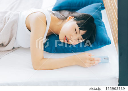 スマホを持ったまま寝落ちした女性 133908589