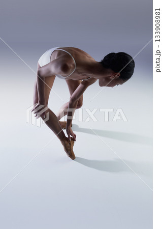 Ballet dancer bending low on pointe creating emotional dynamic tension Ballet dancer bending low on pointe creating emotional dynamic tension 133908981