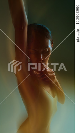Emotional dancer portrait with raised arm and soft glowing motion in warm tones 133908996