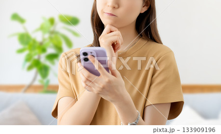 スマートフォンを見て考えごとをする女性 133909196