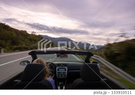 Young woman driving convertible along scenic ocean coast and mountain road at sunset, carefree summer vacation, travel freedom and adventure on coastal highway Young woman driving convertible along scenic ocean coast and mountain road at sunset, carefree summer vacation, travel freedom and adventure on coastal highway 133910511