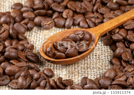 Artistic close-up of coffee beans in a wooden spoon on rustic table Artistic close-up of coffee beans in a wooden spoon on rustic table 133911374