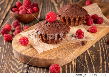 Gourmet chocolate muffins topped with fresh raspberries for a tasty delight Gourmet chocolate muffins topped with fresh raspberries for a tasty delight 133911384