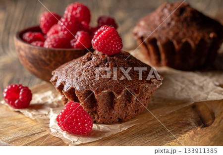 Freshly baked chocolate muffins artfully adorned with luscious ripe raspberries Freshly baked chocolate muffins artfully adorned with luscious ripe raspberries 133911385
