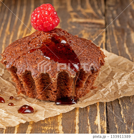Delicious chocolate muffin topped with fresh raspberries close-up view Delicious chocolate muffin topped with fresh raspberries close-up view 133911389