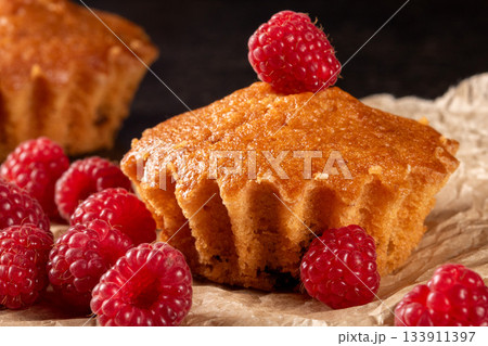 Lemon muffins surrounded by juicy raspberries on a cozy kitchen table scene Lemon muffins surrounded by juicy raspberries on a cozy kitchen table scene 133911397