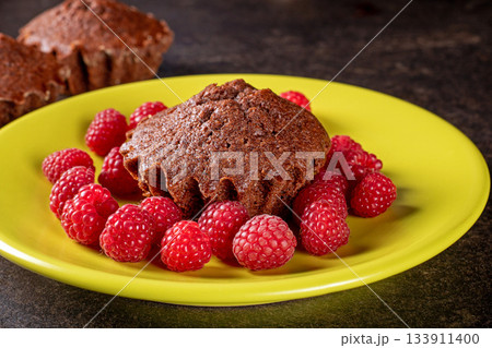 Delicious muffin on a bright green plate surrounded by fresh raspberries 133911400