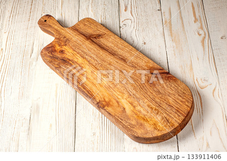 Rustic kitchen scene featuring a poplar wood cutting board on whitewashed table 133911406