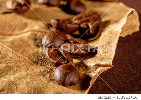 Close-up shot of coffee beans on a rustic dry almond leaf background Close-up shot of coffee beans on a rustic dry almond leaf background 133911416