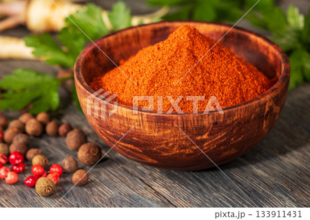Artistic close-up of red ground pepper in a handcrafted wooden bowl 133911431