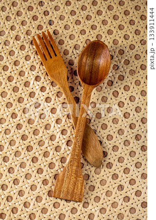 Top view of vintage wooden fork and spoon on rattan napkin background Top view of vintage wooden fork and spoon on rattan napkin background 133911444