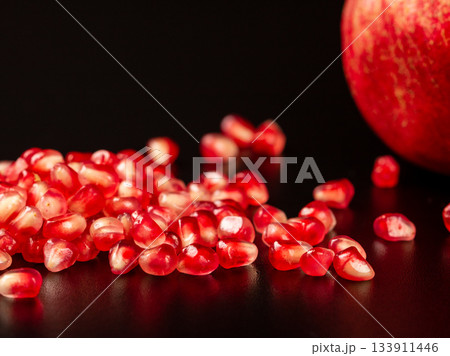 Close-up of pomegranate fruit with vibrant seeds on black background 133911446