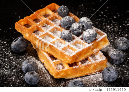 Soft and sweet belgian waffles with juicy blueberries and powdered sugar dusting 133911450
