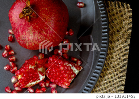 Whole and sliced pomegranate on a vintage metal plate viewed from above 133911455