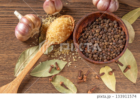 Kitchen table spices: bay leaf, garlic cloves, pepper, and whole cloves in natural light Kitchen table spices: bay leaf, garlic cloves, pepper, and whole cloves in natural light 133911574