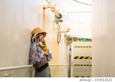 船内の通路で麦わら帽子を被りひまわりを持つアジア人女性 133911621