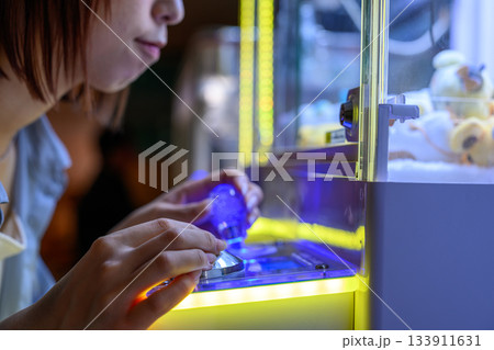 クレーンゲームに熱中する若い女性のクローズアップ 133911631