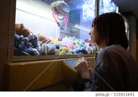 フェリー船内ゲームセンターでクレーンゲームに挑む女性の横顔 133911641