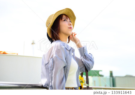 麦わら帽子をかぶり船上から空を見上げる若い女性 麦わら帽子をかぶり船上から空を見上げる若い女性 133911643