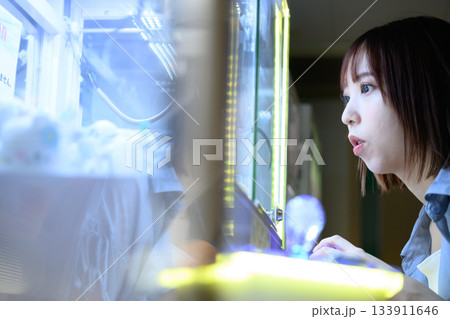 UFOキャッチャーに熱中する若い女性の真剣な横顔 UFOキャッチャーに熱中する若い女性の真剣な横顔 133911646
