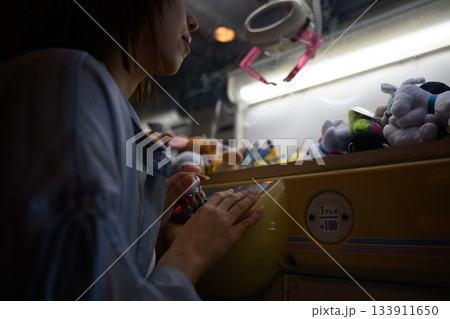 クレーンゲームに集中する若い女性の横顔 クレーンゲームに集中する若い女性の横顔 133911650
