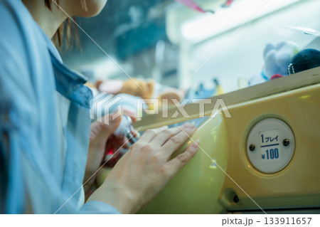 フェリーのゲームセンターでクレーンゲームに夢中になる女性 133911657