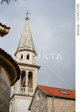 Detailed close-up of the bell and window of a historic church tower in Old Town Budva, Montenegro. Showcases medieval architecture, stone textures, and classic Mediterranean details. Ideal for travel 133911780