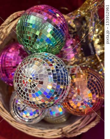 Christmas Colorful disco ornaments stacked in festive basket. Holiday variety, Christmas decor, winter celebration, market mood and glitter joy create bright cheerful party atmosphere. 133912961