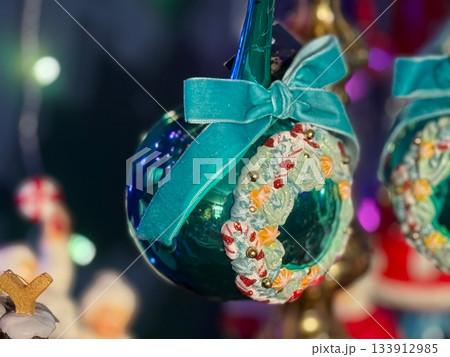 Shiny teal Christmas bauble decorated with candy-inspired wreath and velvet bow. Festive elegance, sweet holiday fantasy, winter charm and magical celebration mood. Shiny teal Christmas bauble decorated with candy-inspired wreath and velvet bow. Festive elegance, sweet holiday fantasy, winter charm and magical celebration mood. 133912985