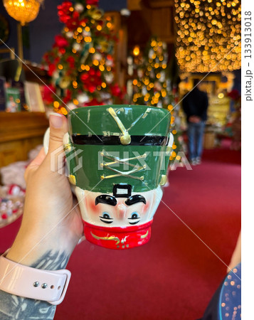Christmas Nutcracker mug held in a festive holiday shop. Seasonal joy, playful tradition and warm winter storytelling enhancing decorative atmosphere and charming holidays celebration 133913018