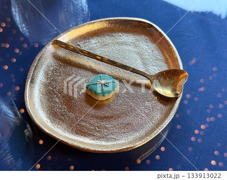 Christmas Tiny iced cookie resting on a golden plate. Gentle celebration, winter calm and holiday simplicity forming delicate seasonal storytelling and warm atmosphere 133913022