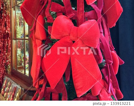 Red velvet bows decorating a festive Christmas tree. Seasonal elegance, joyful tradition and warm holiday atmosphere forming emotional celebration and decorative storytelling for winter magic 133913221