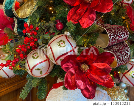 Holiday Christmas ornaments and red florals displayed on evergreen branches. Seasonal mood and decorative elegance spirit of celebration. Holiday Christmas ornaments and red florals displayed on evergreen branches. Seasonal mood and decorative elegance spirit of celebration. 133913232