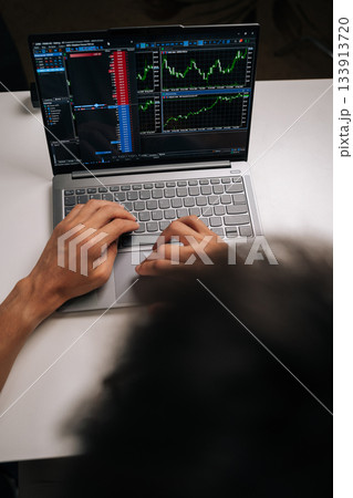 Vertical top view of trader man trading online, monitoring stock market chart and financial data on laptop, analyzing investments and making decisions for wealth management using digital technology. 133913720