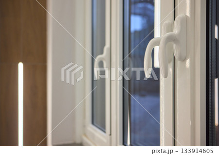 A contemporary window equipped with an open handle that offers a beautiful view of the cityscape 133914605