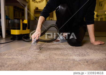 Maintenance technician performs thorough carpet extraction, Professional technician utilizes portable tool to deeply clean and rejuvenate stained commercial carpets 133914618