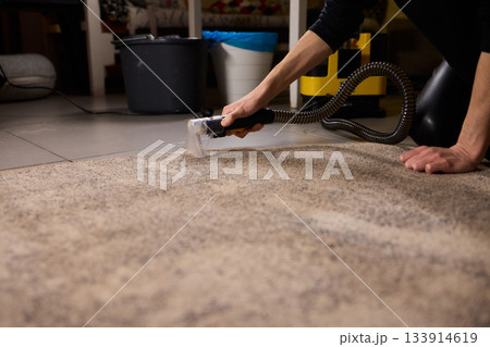 Maintenance technician performs thorough carpet extraction, Professional technician utilizes portable tool to deeply clean and rejuvenate stained commercial carpets 133914619
