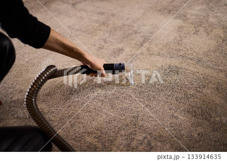 Maintenance technician performs thorough carpet extraction, Professional technician utilizes portable tool to deeply clean and rejuvenate stained commercial carpets 133914635