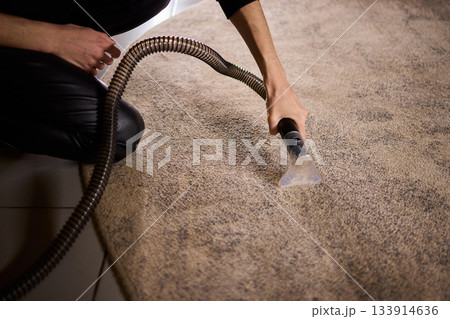 Maintenance technician performs thorough carpet extraction, Professional technician utilizes portable tool to deeply clean and rejuvenate stained commercial carpets 133914636