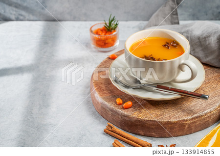 Sea buckthorn herbal tea in a cup on a wooden board on a light background Sea buckthorn herbal tea in a cup on a wooden board on a light background 133914855