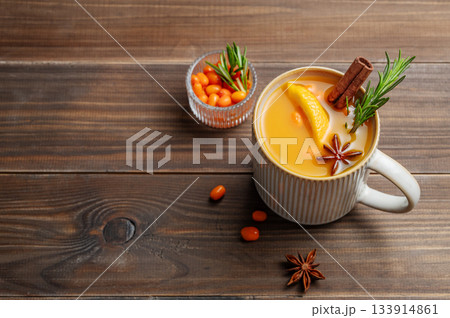 Sea buckthorn herbal tea in a cup on a wooden background with spices and  berries. 133914861